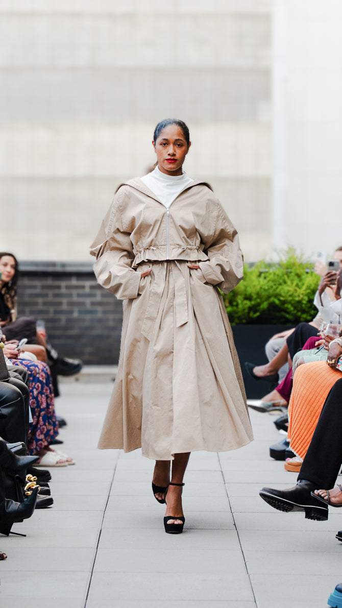 Itaty Rosero wearing a beige trench jacket and skirt set on Megan Renee's SS26 fashion show runway.
