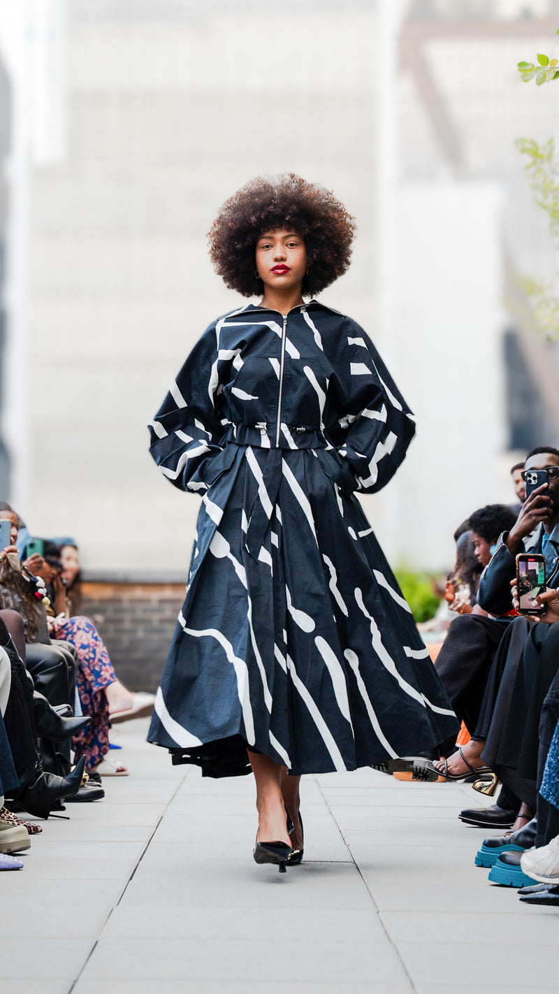 Siyann Smith walking Megan Renee's SS26 fashion show wearing a black and white patterned jacket and skirt set.